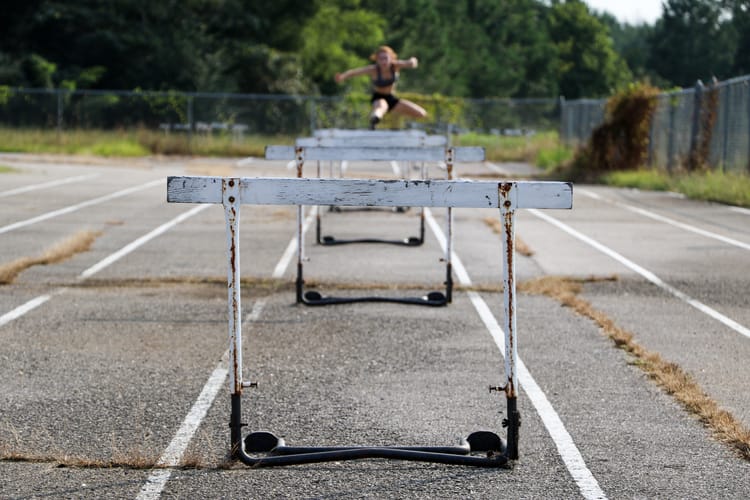 a series of old wooden hurdles on a weed-grown track