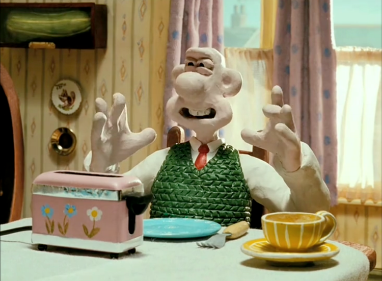 screenshot of Wallace from The Wrong Trousers, waggling his fingers as his is saying, "Crackin' toast, Gromit!"