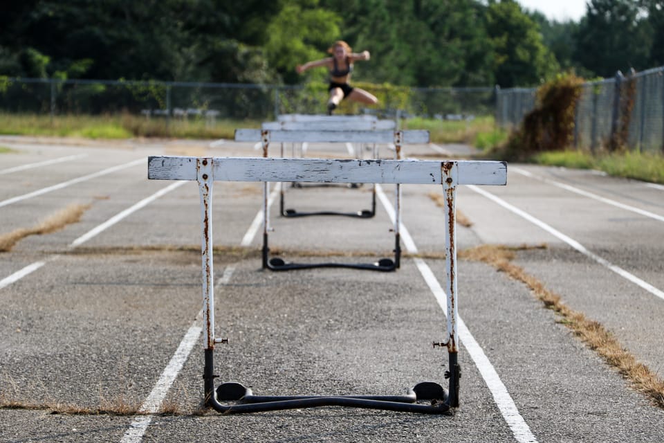 a series of old wooden hurdles on a weed-grown track