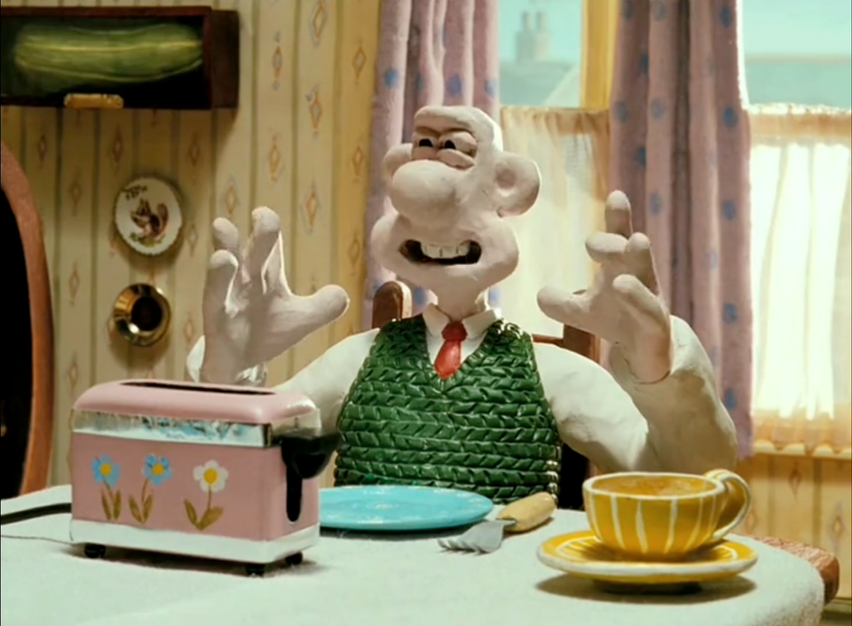screenshot of Wallace from The Wrong Trousers, waggling his fingers as his is saying, "Crackin' toast, Gromit!"